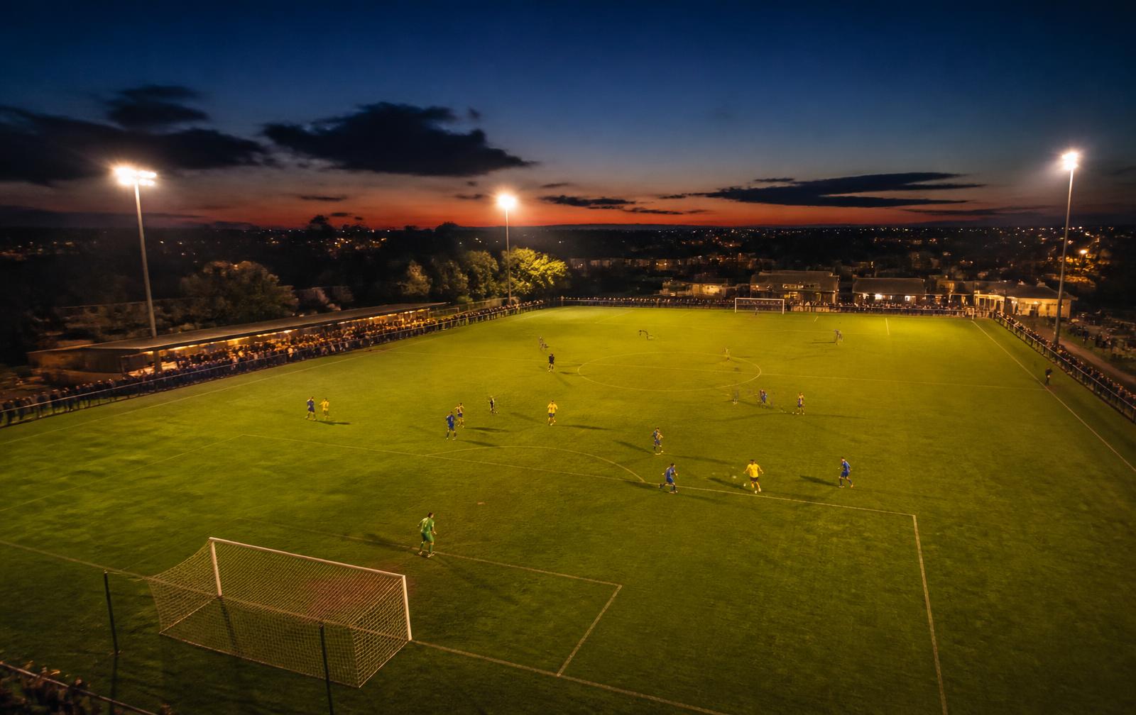 Partido de fútbol base en un campo comunitario al anochecer